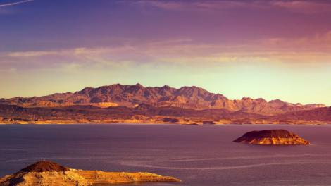 A boulder peeks out on the surface of a peaceful reservoir