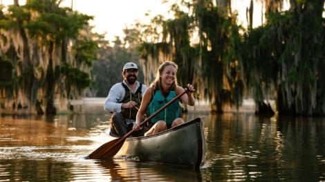 Una pareja haciendo canotaje junto a cipreses en Lake Martin, cerca de Breaux Bridge, Luisiana Una pareja haciendo canotaje junto a cipreses en Lake Martin, cerca de Breaux Bridge, Luisiana
