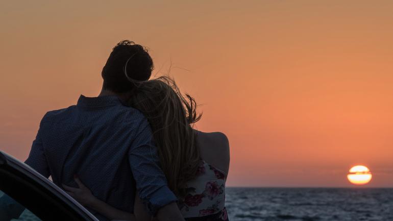 Couple on a road trip taking in the sunset from the Skyway Fishing Pier State Park near St. Petersburg, Florida