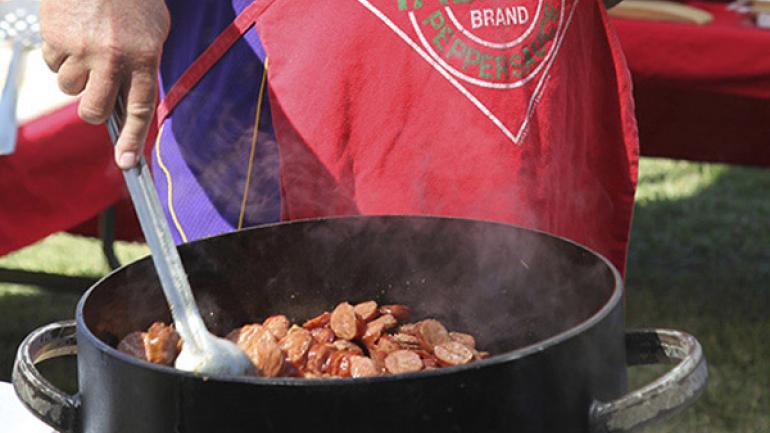 Cocinando salchichas en una de sus reconocidas ollas negras durante el festival