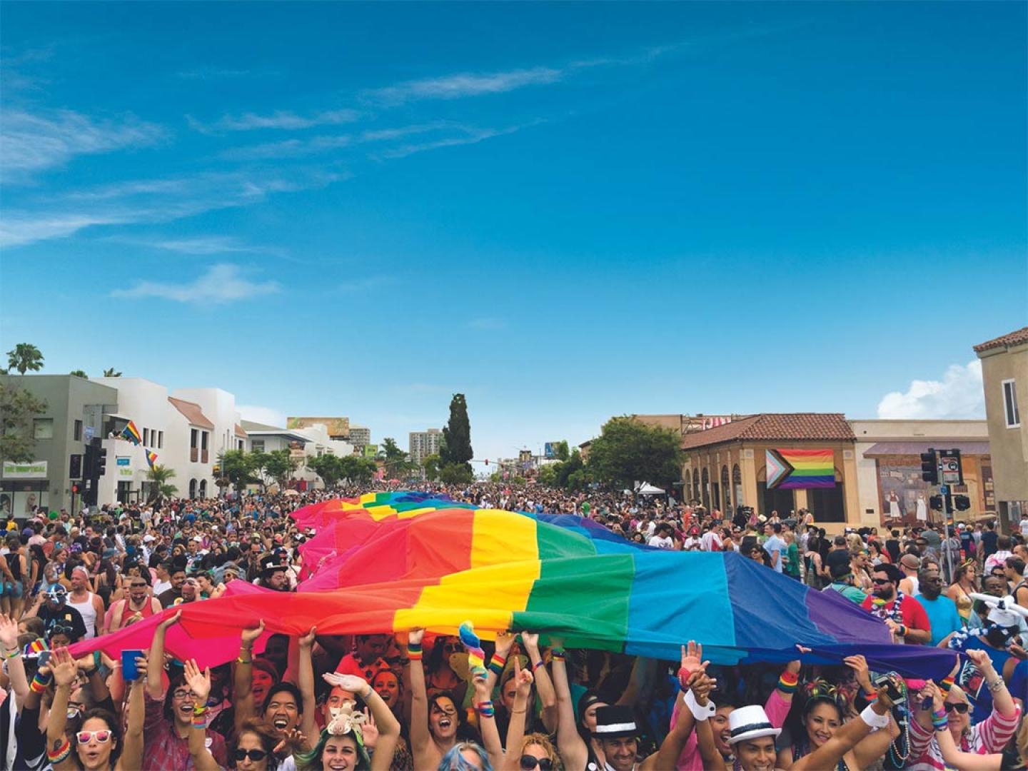 A crowd lifts a rainbow flag during San Diego Pride