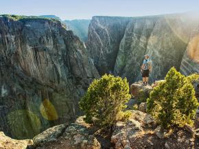 Hiker taking in the depths and striated walls of Colorado’s Black Canyon of the Gunnison National Park Hiker taking in the depths and striated walls of Colorado’s Black Canyon of the Gunnison National Park