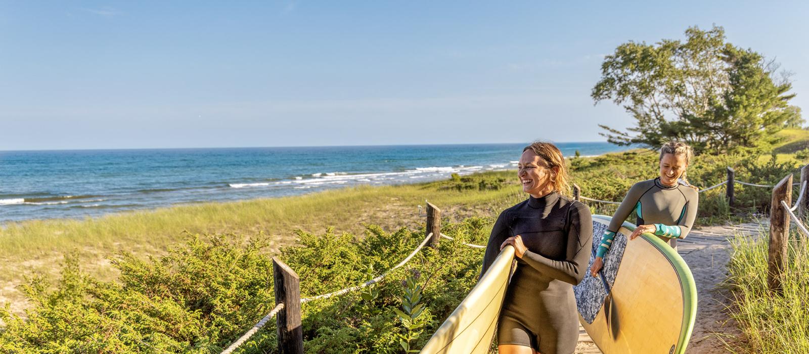 Mujeres llevando tablas de surf de remo en el Kohler-Andrae State Park en Wisconsin
