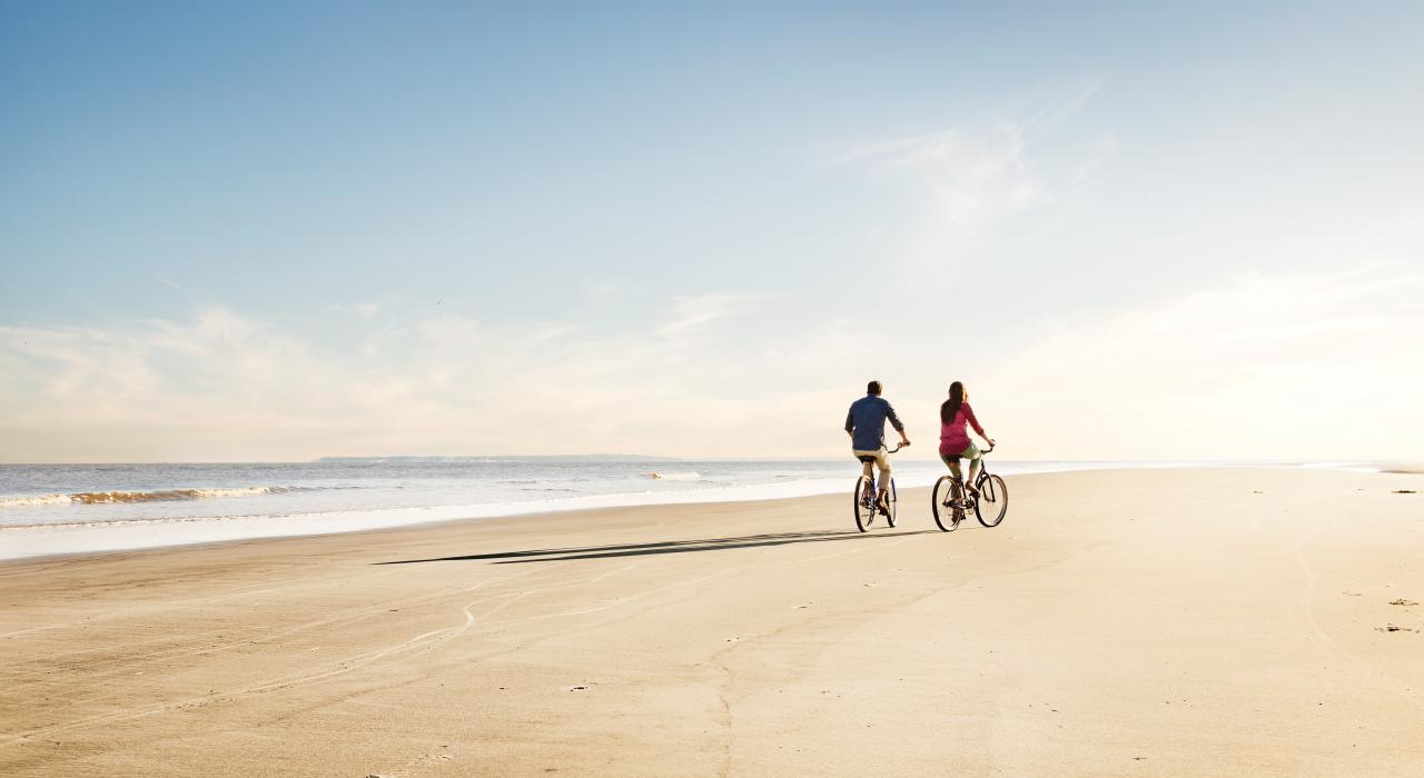 Couple biking along a wide stretch of beach