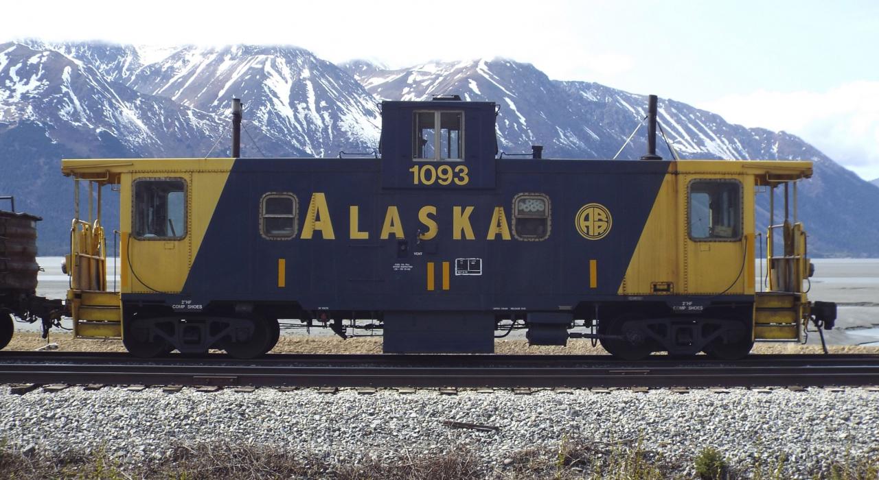 Train caboose passing by stunning mountain ranges