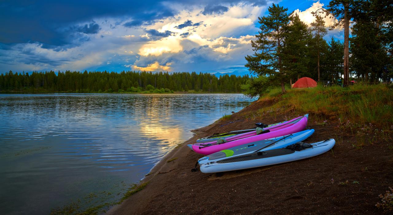 Lakeside campsite with canoes and paddleboards prepped for adventure