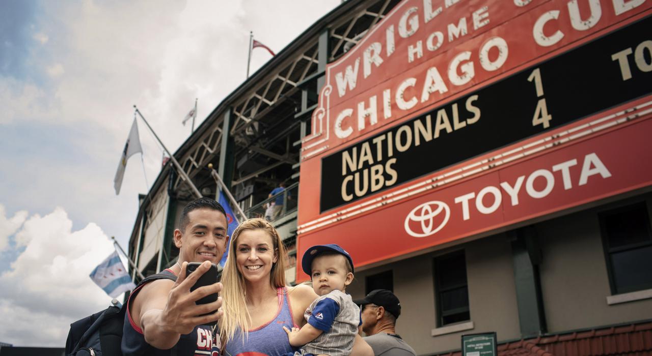 Visitantes tomándose una selfi frente la icónica marquesina de Wrigley Field en Chicago, Illinois