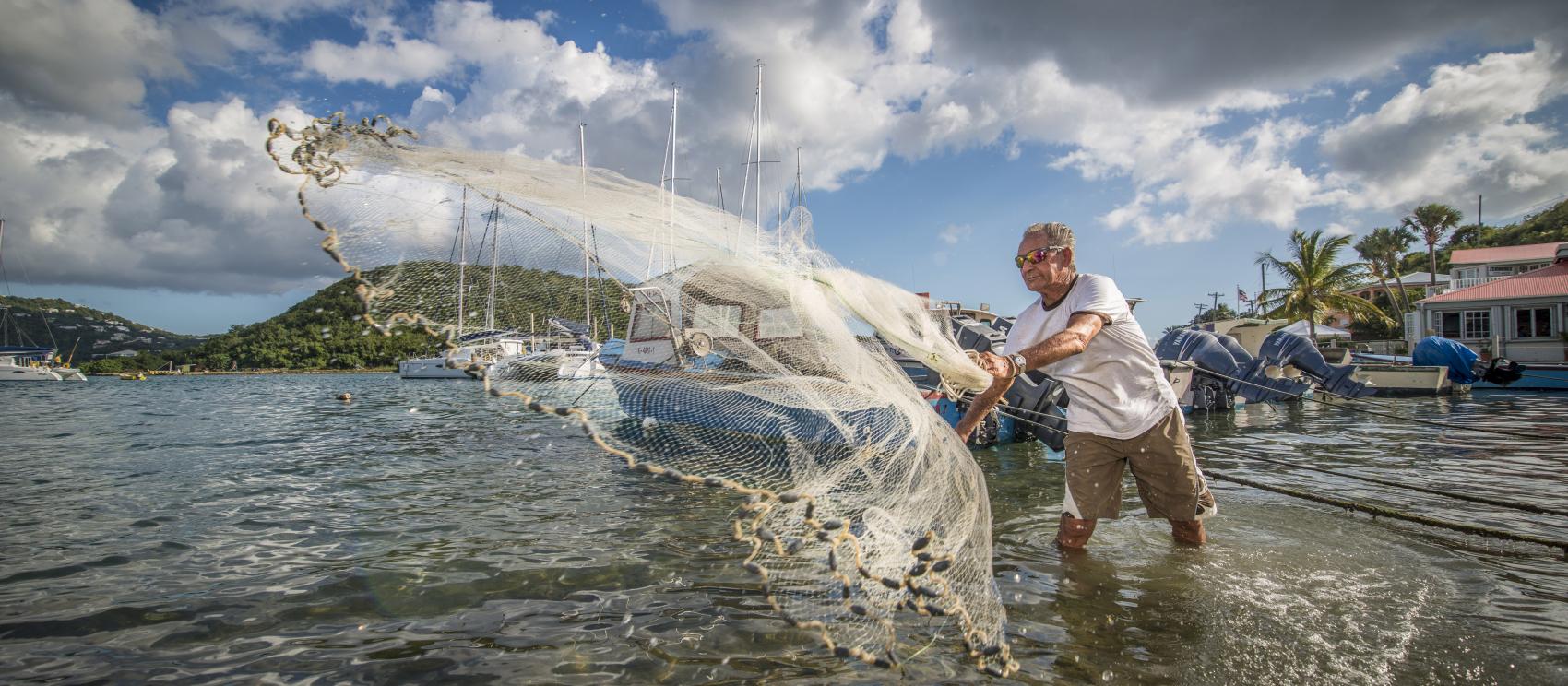 A fisherman casts his net in Frenchtown, St. Thomas